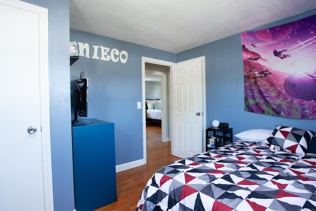 bedroom with baseboards and wood finished floors