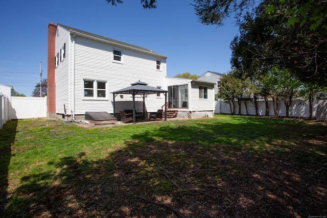 back of house featuring a gazebo, a fenced backyard, a chimney, a patio area, and a lawn