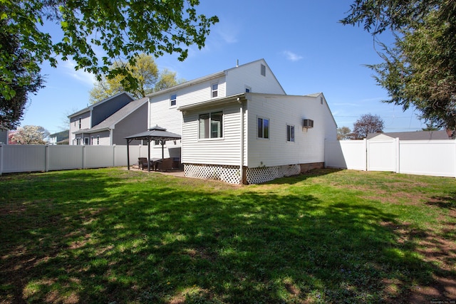 back of property with a yard, a gazebo, and a fenced backyard