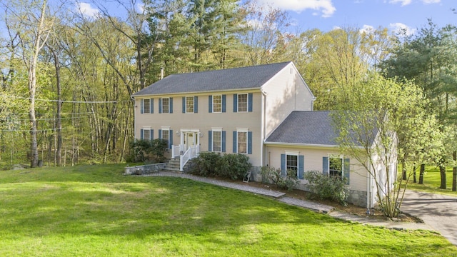 colonial-style house with roof with shingles and a front yard