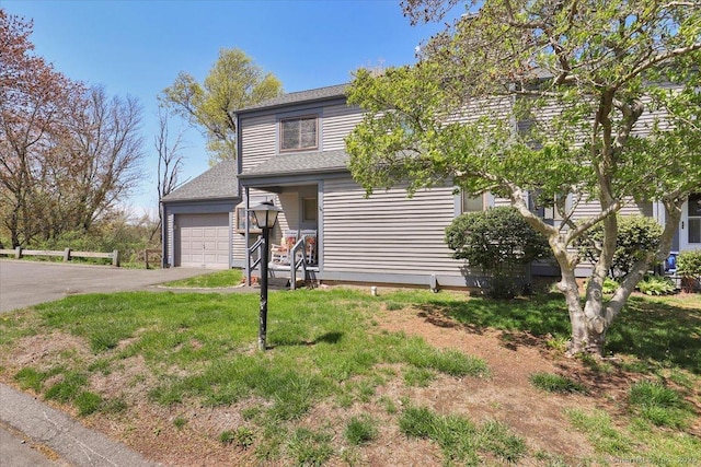 view of front of property featuring a front lawn, roof with shingles, and driveway