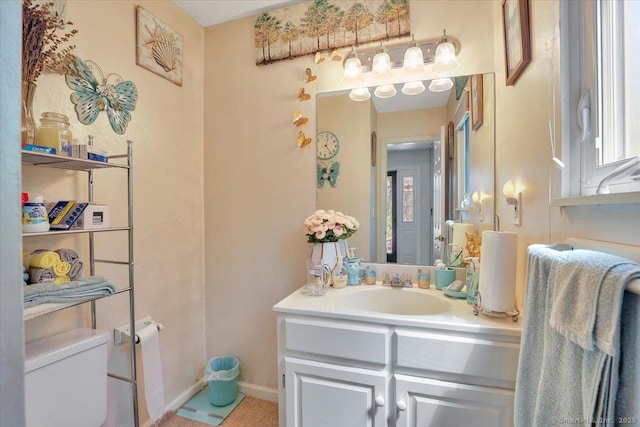 bathroom featuring toilet, baseboards, and vanity