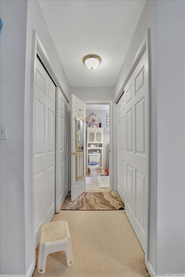 hallway featuring carpet flooring and a textured ceiling