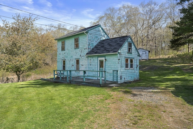 back of property featuring a shingled roof, a yard, and a deck