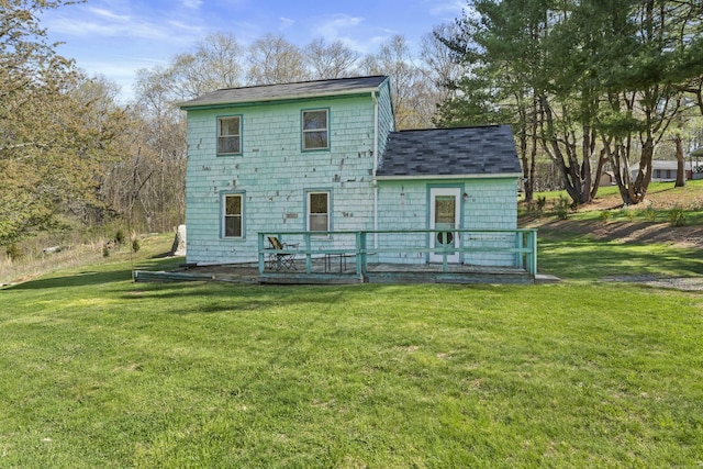 rear view of house featuring a yard, a deck, and a shingled roof