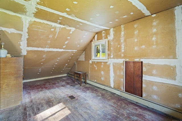 additional living space with visible vents, vaulted ceiling, hardwood / wood-style floors, and baseboard heating