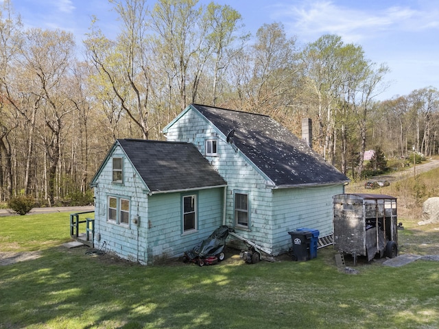 exterior space featuring a yard, a shingled roof, and a chimney