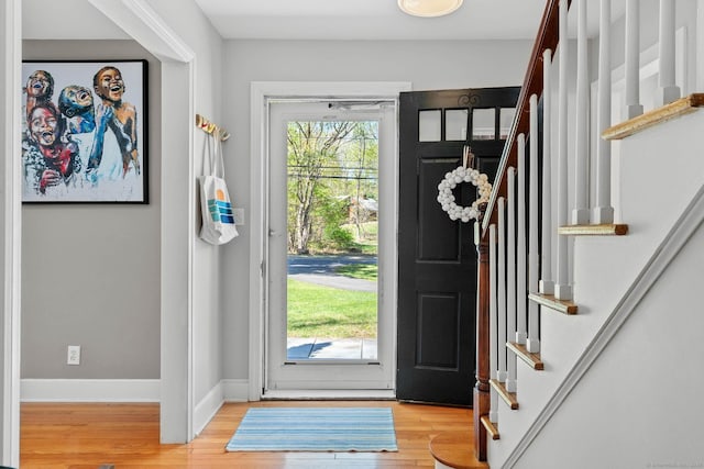 foyer entrance featuring baseboards, wood finished floors, and stairway