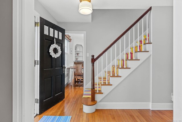 entrance foyer with baseboards, stairs, and hardwood / wood-style floors