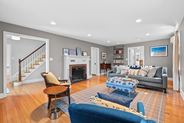 living room with stairs, baseboards, light wood finished floors, and a fireplace