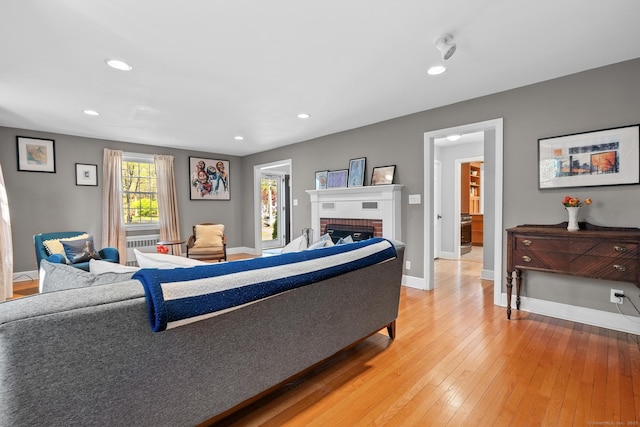 living area with a brick fireplace, recessed lighting, baseboards, and light wood-type flooring