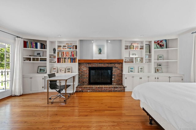 bedroom with a brick fireplace and light wood-type flooring