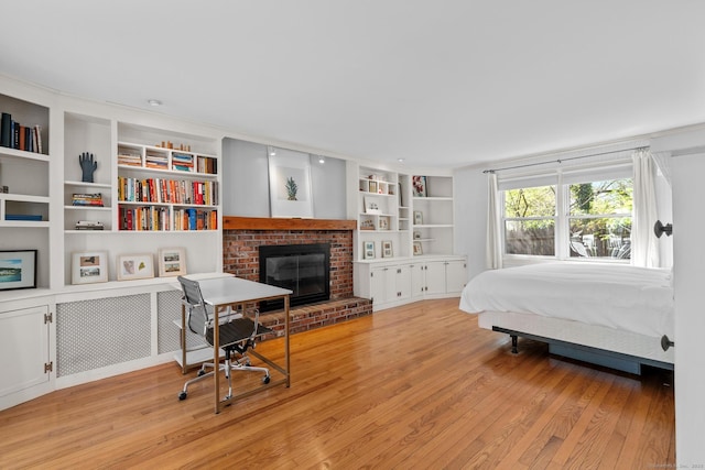 bedroom featuring a fireplace and light wood-style flooring