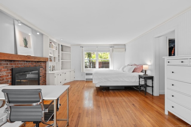 bedroom featuring radiator, wood-type flooring, a brick fireplace, and a wall mounted air conditioner