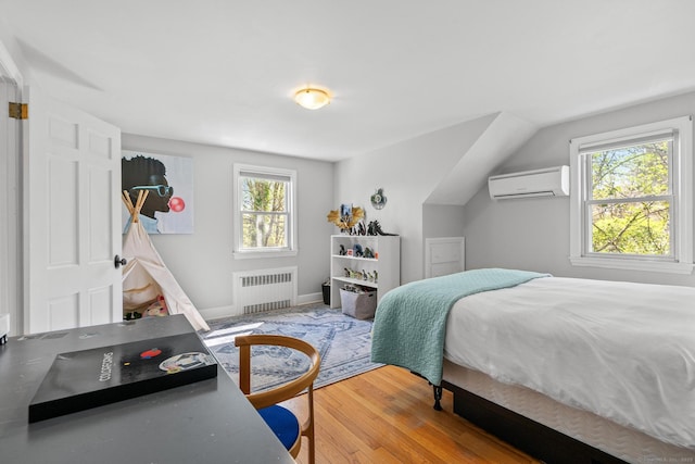 bedroom with wood finished floors, a wall unit AC, radiator heating unit, and multiple windows