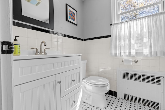 bathroom with vanity, radiator, toilet, and tile walls