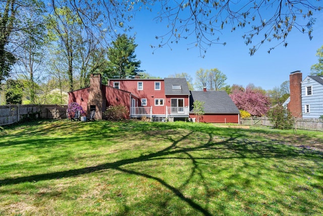 back of property with a lawn, a wooden deck, and a fenced backyard