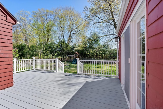 deck featuring a playground, fence, and a lawn