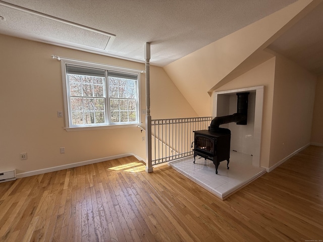 bonus room with vaulted ceiling, baseboards, wood-type flooring, and a wood stove