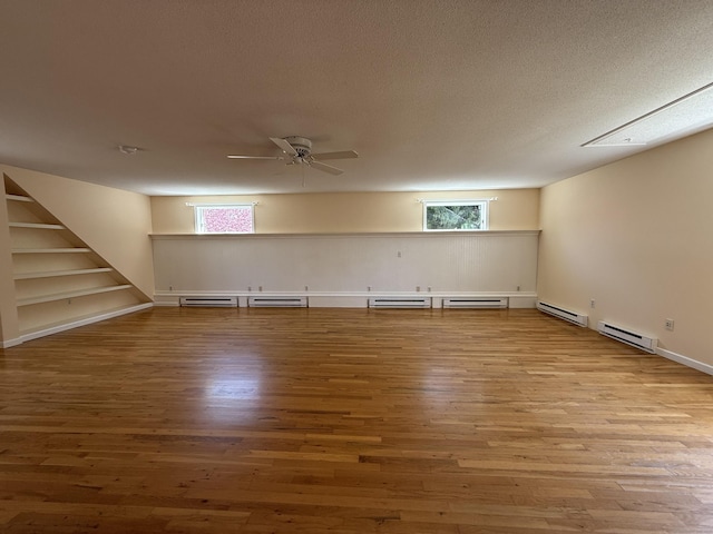 below grade area featuring a ceiling fan, wood finished floors, and a baseboard radiator