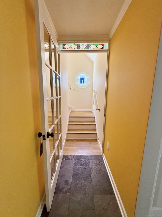 corridor with french doors, crown molding, stairway, baseboards, and stone tile flooring