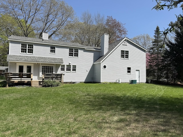 back of house featuring central AC, a lawn, a wooden deck, and a chimney