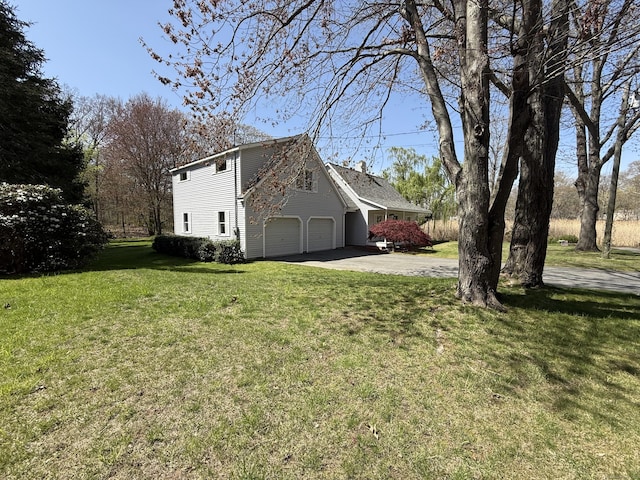 view of home's exterior with concrete driveway, a lawn, and an attached garage