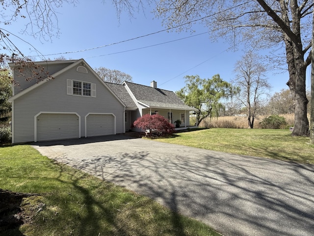 view of front of property with a front lawn, an attached garage, a chimney, a porch, and driveway
