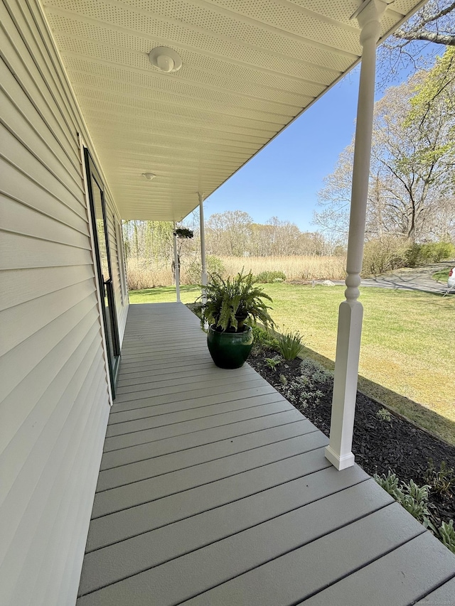 wooden terrace featuring covered porch and a yard