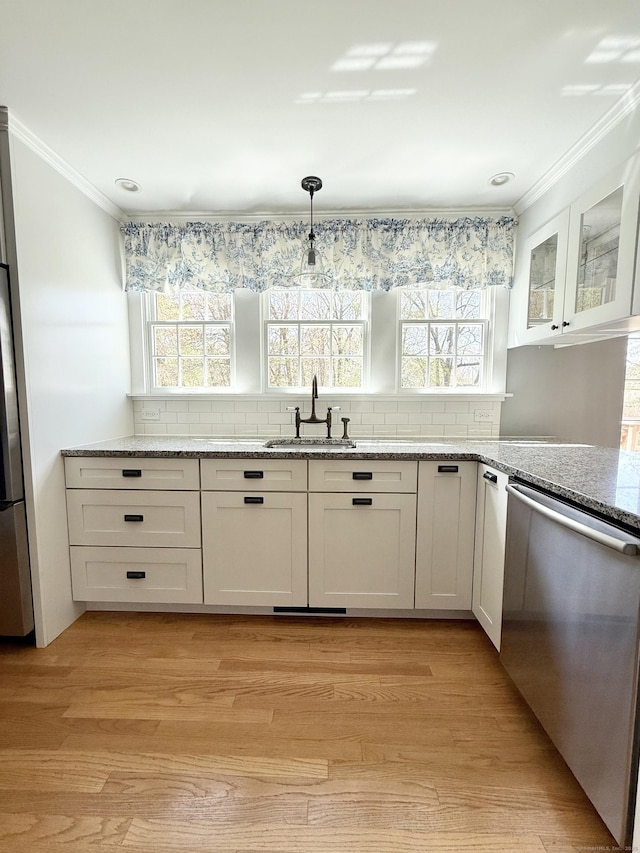 kitchen featuring crown molding, decorative backsplash, white cabinetry, a sink, and dishwasher