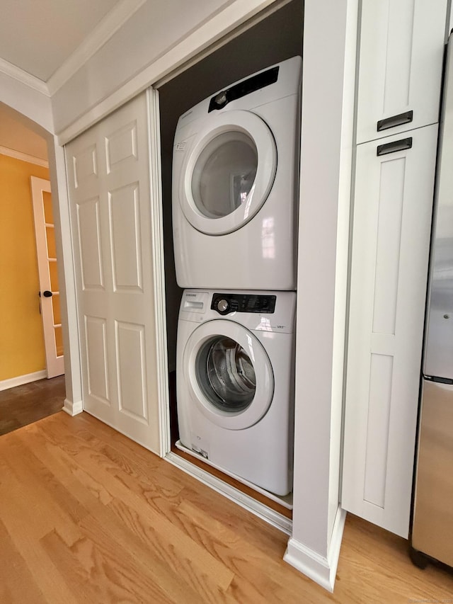 washroom with laundry area, baseboards, ornamental molding, stacked washer and clothes dryer, and light wood-style flooring