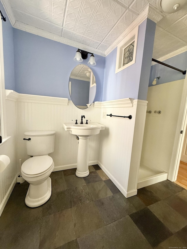 full bathroom with an ornate ceiling, a walk in shower, toilet, and wainscoting