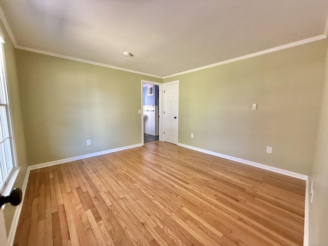 unfurnished room with baseboards, ornamental molding, and light wood-style flooring