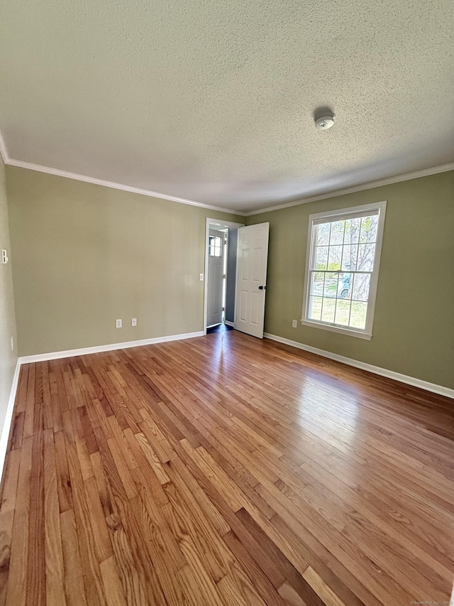 unfurnished living room featuring ornamental molding, a textured ceiling, and wood finished floors