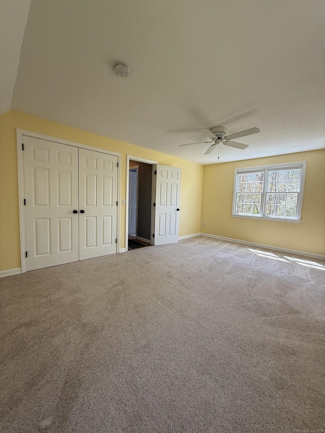 unfurnished bedroom with carpet floors, baseboards, ceiling fan, and two closets