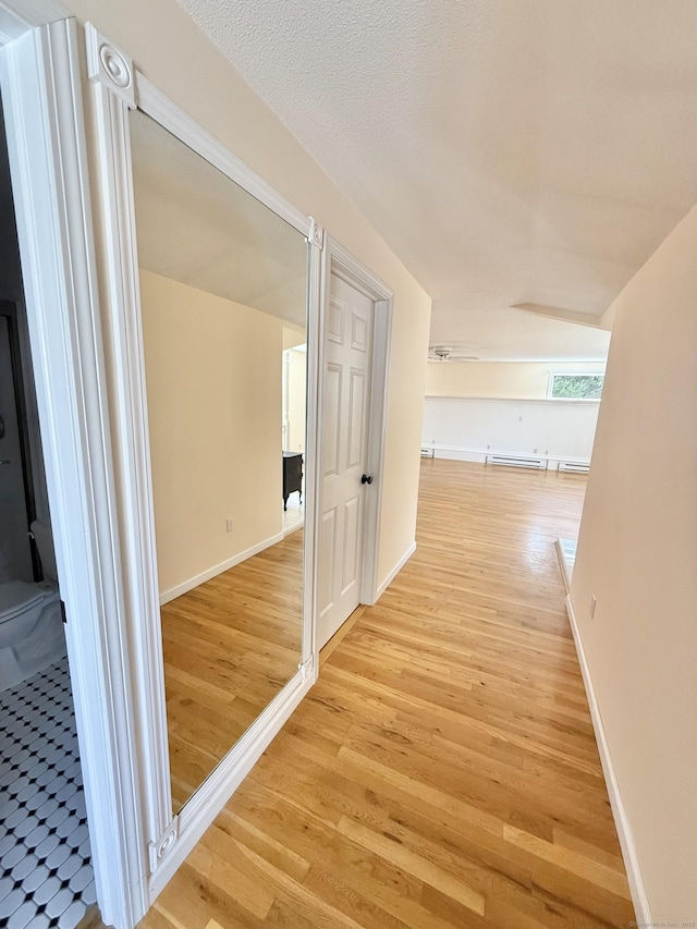 corridor featuring baseboards and light wood finished floors
