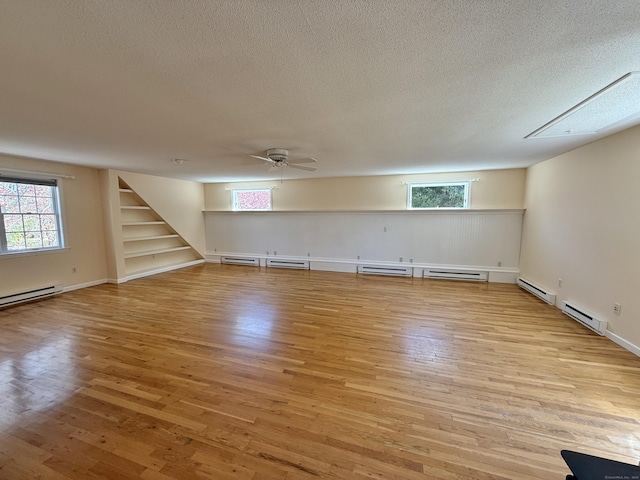 basement with light wood-style floors, a textured ceiling, ceiling fan, and stairway