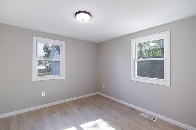 spare room with baseboards, visible vents, light wood-style flooring, and a wealth of natural light