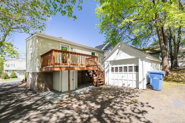 rear view of house featuring an outbuilding, a wooden deck, stairs, and a garage