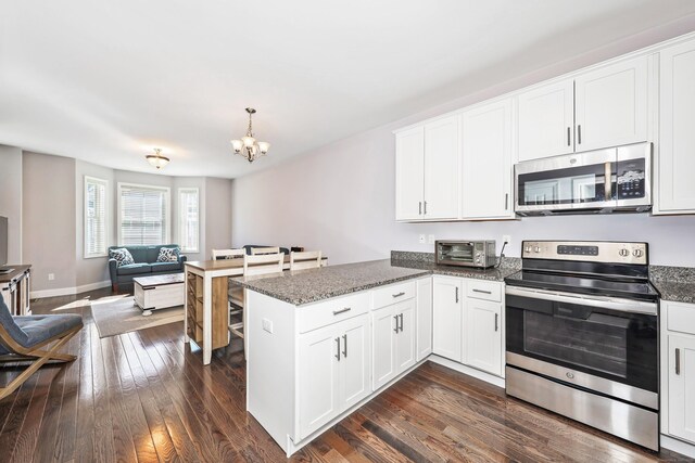 kitchen featuring appliances with stainless steel finishes, a toaster, a peninsula, open floor plan, and an inviting chandelier