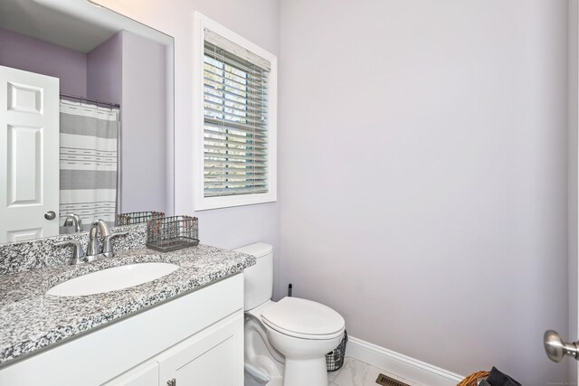 bathroom featuring toilet, baseboards, marble finish floor, and vanity