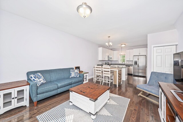 living room with dark wood-type flooring, baseboards, and a notable chandelier