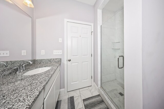 bathroom with vanity, baseboards, a shower stall, and marble finish floor