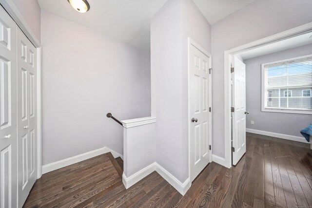 hall featuring baseboards, wood finished floors, and an upstairs landing