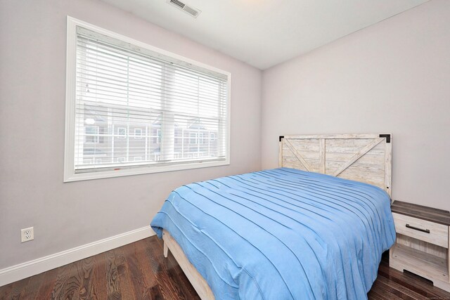 bedroom with visible vents, baseboards, and wood finished floors