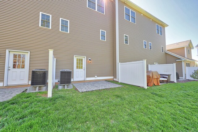 back of property with fence, a patio, a yard, and central AC