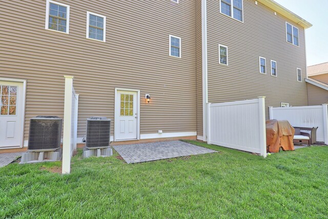 rear view of property with a yard, a patio, fence, and central AC unit