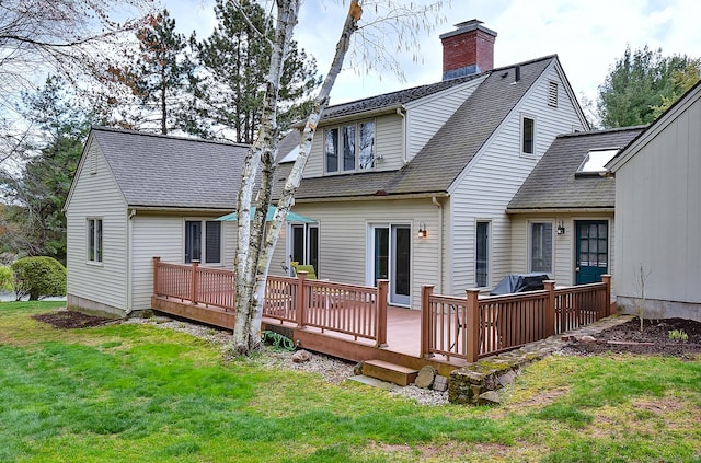back of house featuring a shingled roof, a wooden deck, a yard, and a chimney