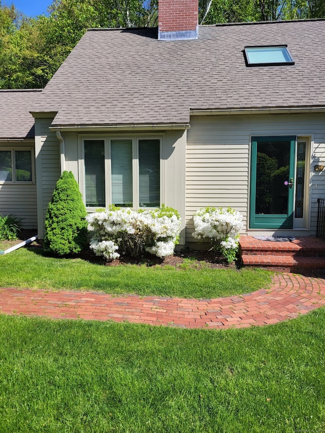 exterior space featuring a lawn, roof with shingles, and a chimney