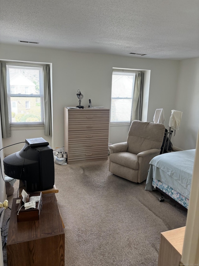 carpeted bedroom featuring multiple windows, a textured ceiling, and visible vents
